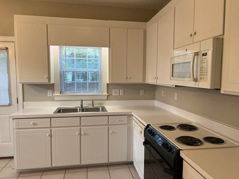 A kitchen with white cabinets and a black stove top.