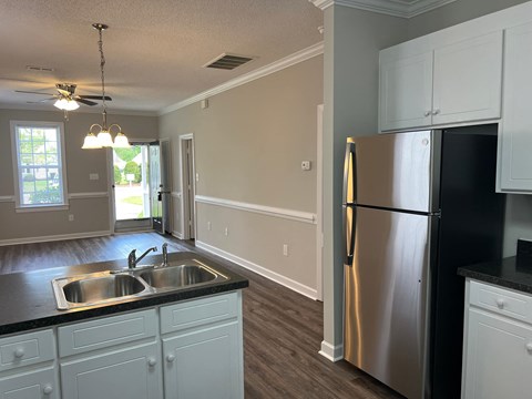 A kitchen with a stainless steel refrigerator and white cabinets.