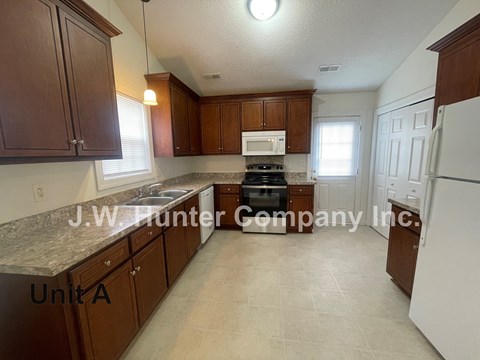 A kitchen with brown cabinets and a white refrigerator.