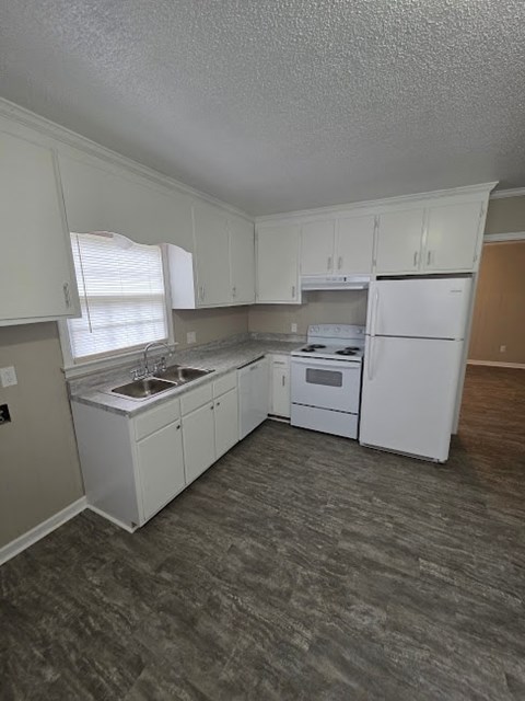 A white kitchen with a sink, stove, and refrigerator.