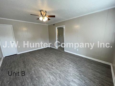 A room with a ceiling fan and a door leading to another room.