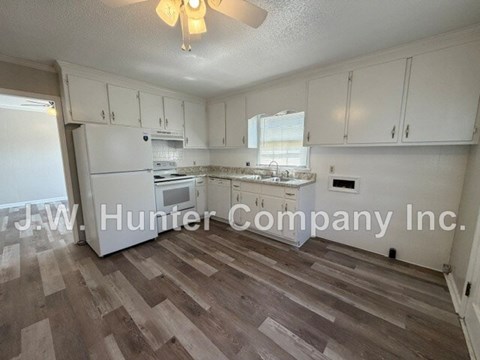 A kitchen with white cabinets and a wooden floor.