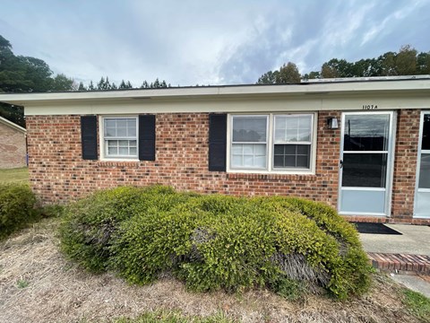 A brick house with a green bush in front.