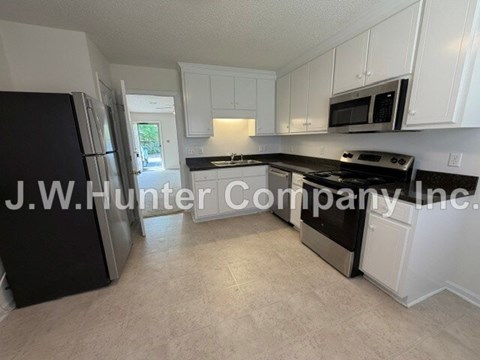 A kitchen with white cabinets and black appliances.