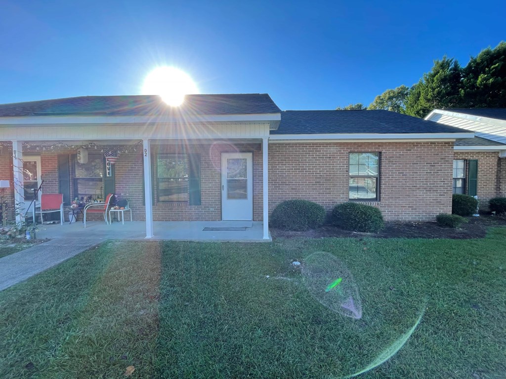 A house with a lawn and a sunny sky above.