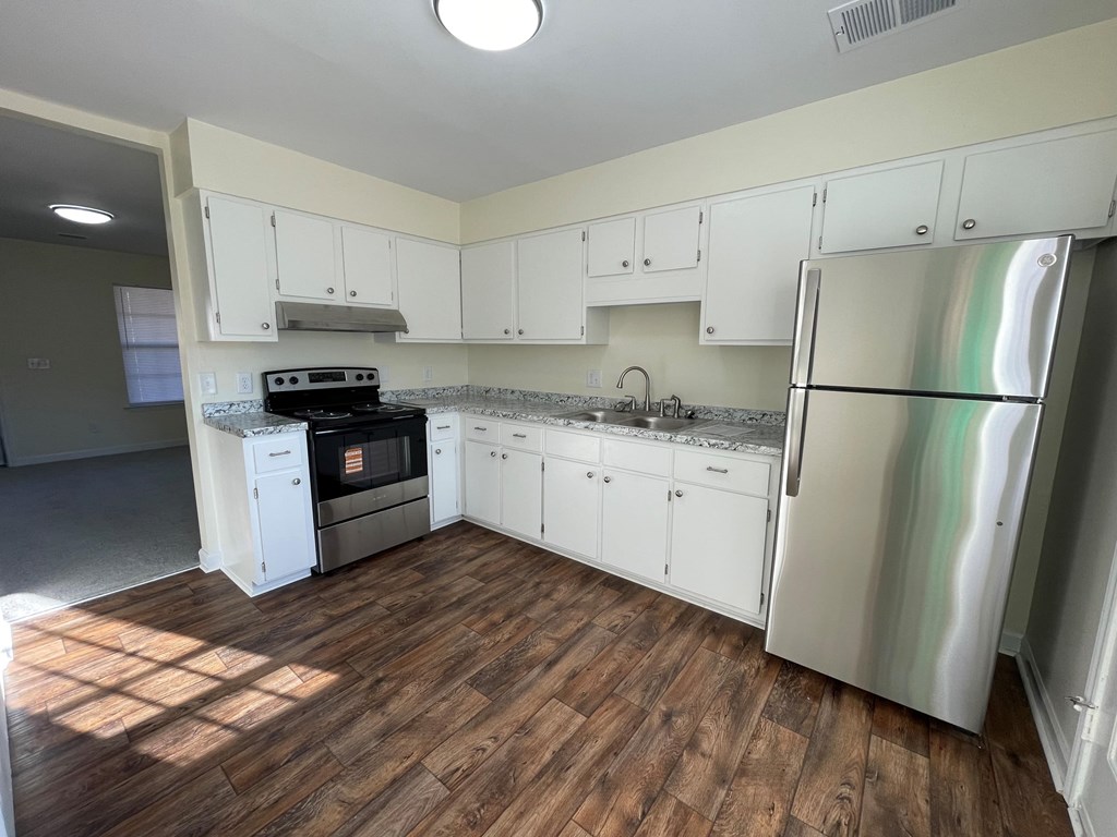 A kitchen with white cabinets and a wooden floor.