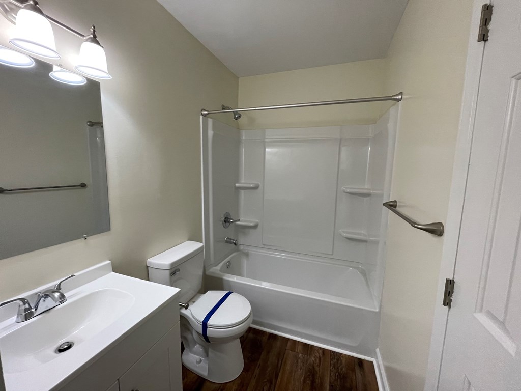 A white bathroom with a toilet, sink, and shower.