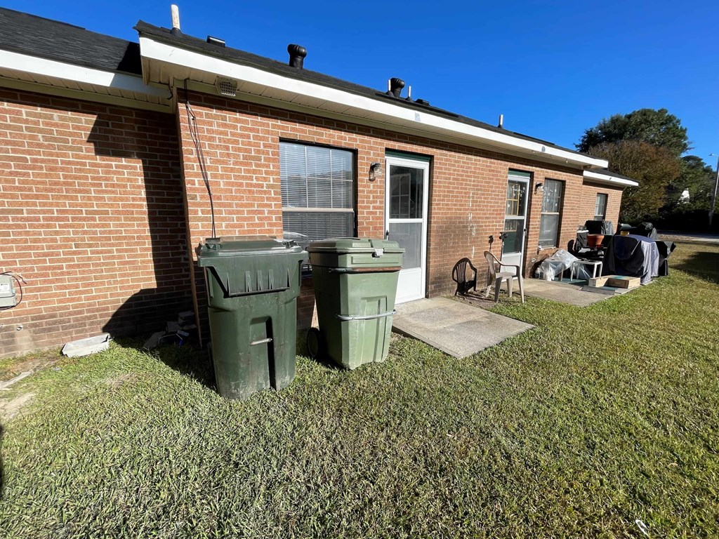 A house with a green trash can in front of it.