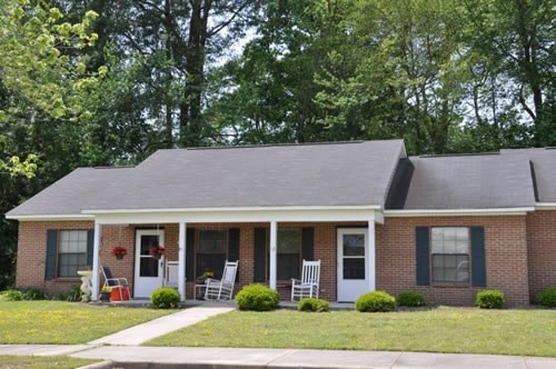 A house with a front porch and a red flower on the door.