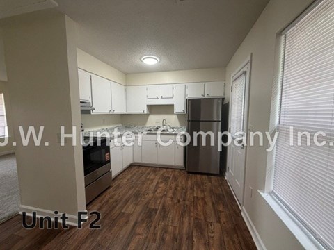 A kitchen area with wooden floors and white cabinets.