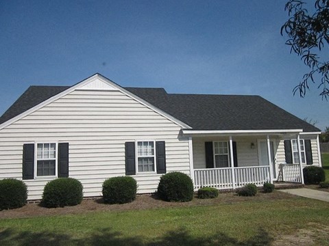 a white house with a porch and a lawn