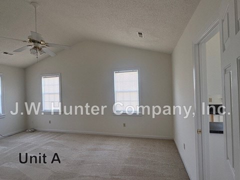 A spacious room with a ceiling fan and carpeted floor.