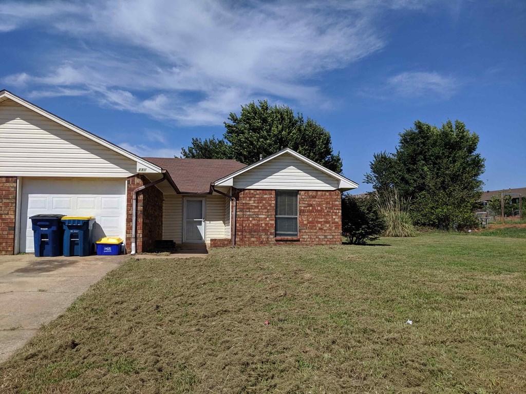 a brick house with a grassy yard and a driveway