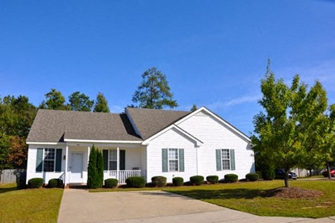 A white house with a grey roof and a driveway in front.