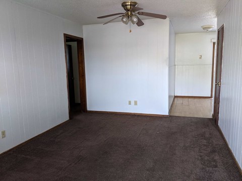 A room with a ceiling fan and carpeted floor.
