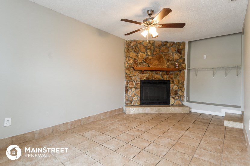 the living room has a stone fireplace and tile flooring