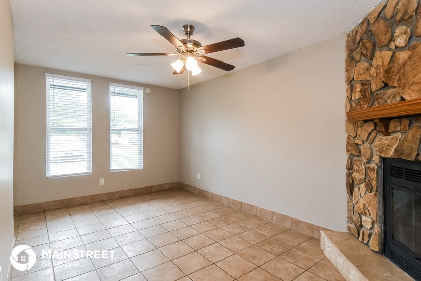 an empty living room with a fireplace and a ceiling fan