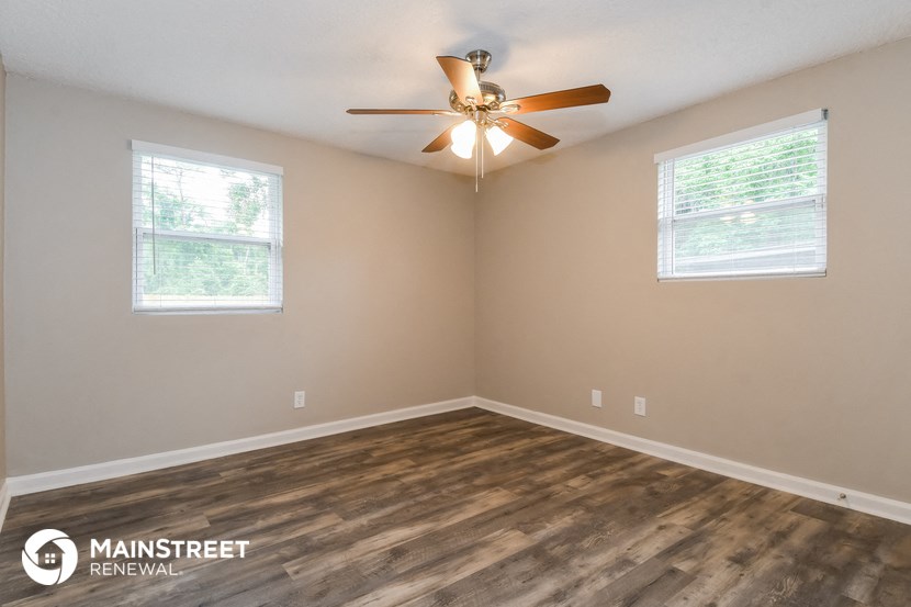 the spacious living room with hardwood floors and a ceiling fan