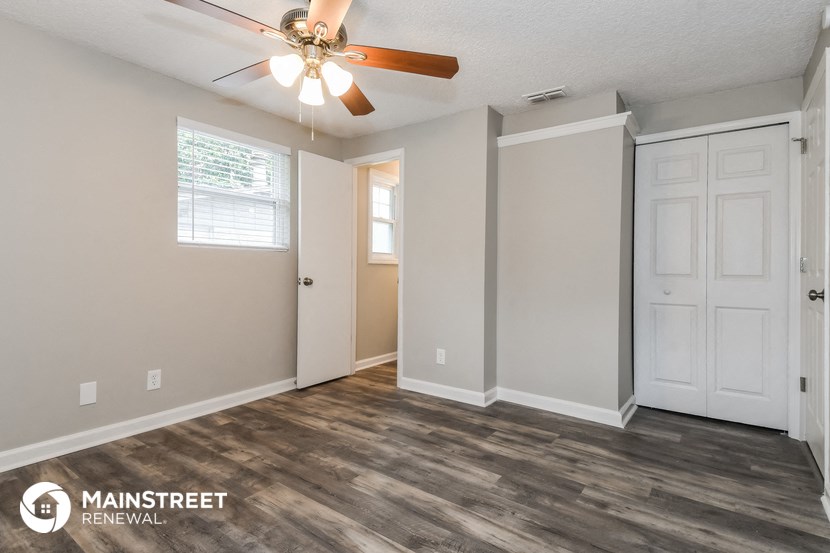 the spacious living room with ceiling fan and white doors