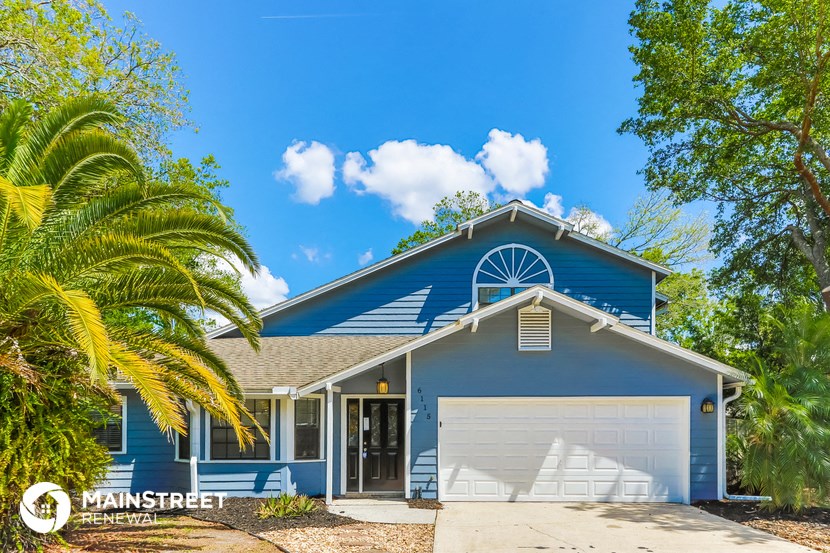 a blue house with a garage door and a palm tree
