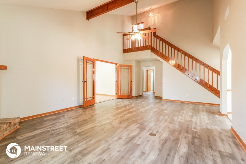 an empty living room with wood floors and a staircase