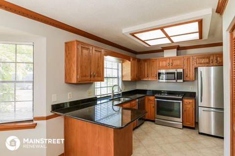 a kitchen with wooden cabinets and a black counter top