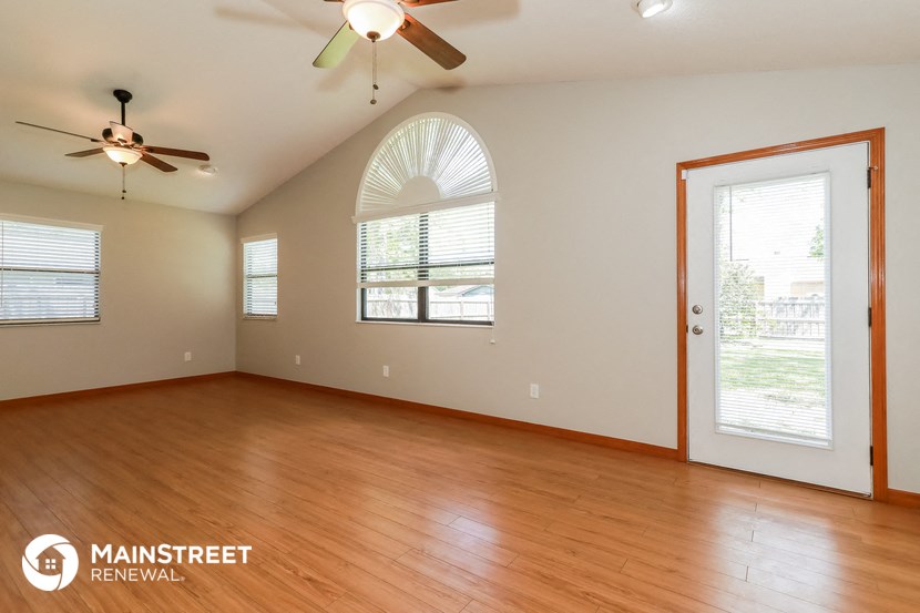 an empty living room with wood floors and a ceiling fan