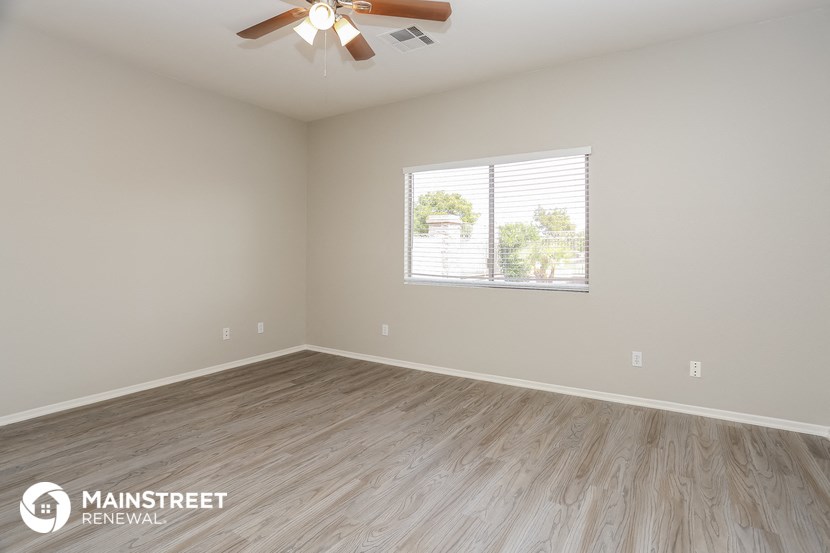 the spacious living room with wood flooring and a ceiling fan