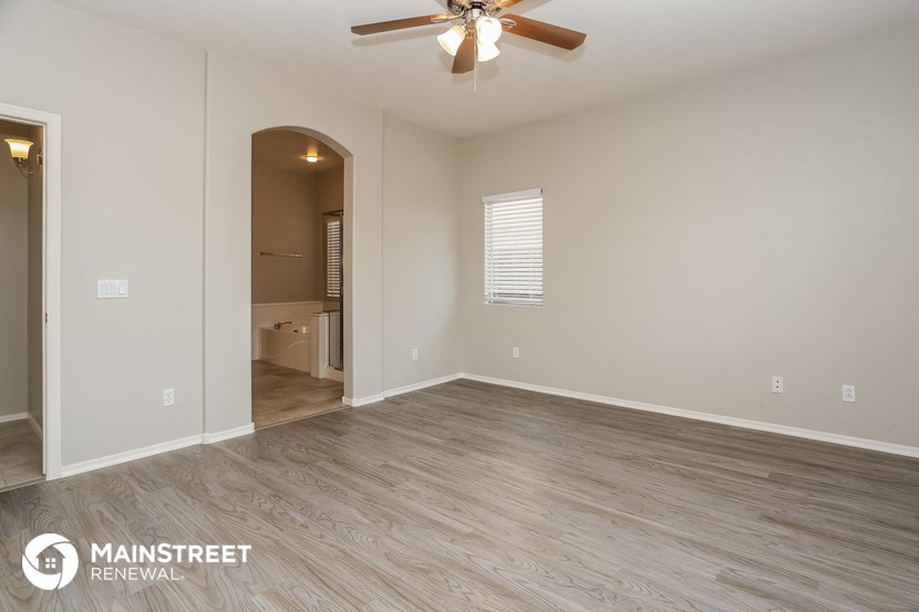 the spacious living room with wood flooring and a ceiling fan