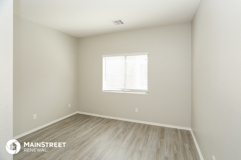 the spacious living room with wood flooring and a window