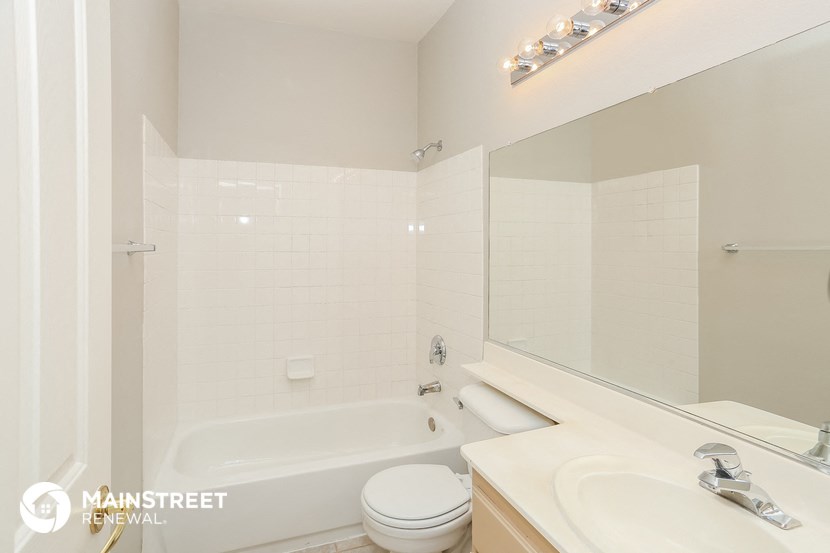 a white bathroom with a tub and a sink and a mirror