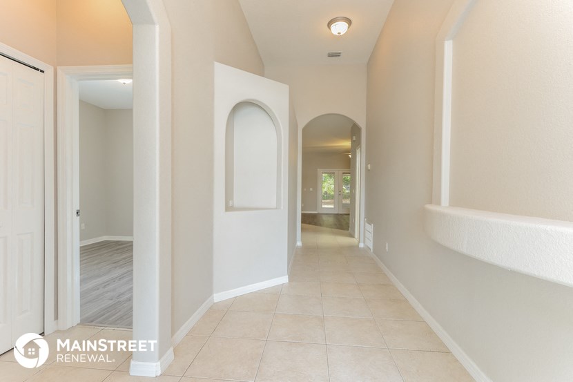 a hallway with white walls and a tile floor and an arched door
