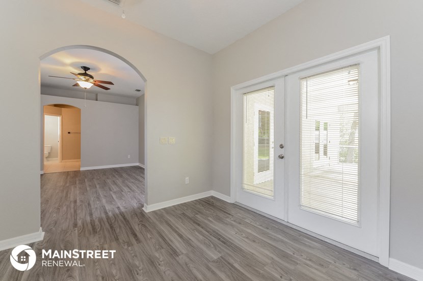 the living room and dining room of an empty house with a ceiling fan