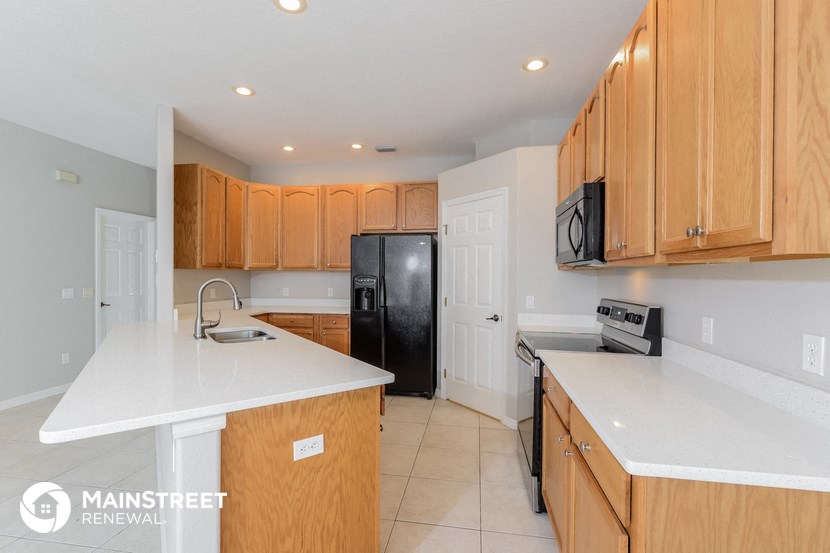 a kitchen with white counter tops and wooden cabinets and a black refrigerator