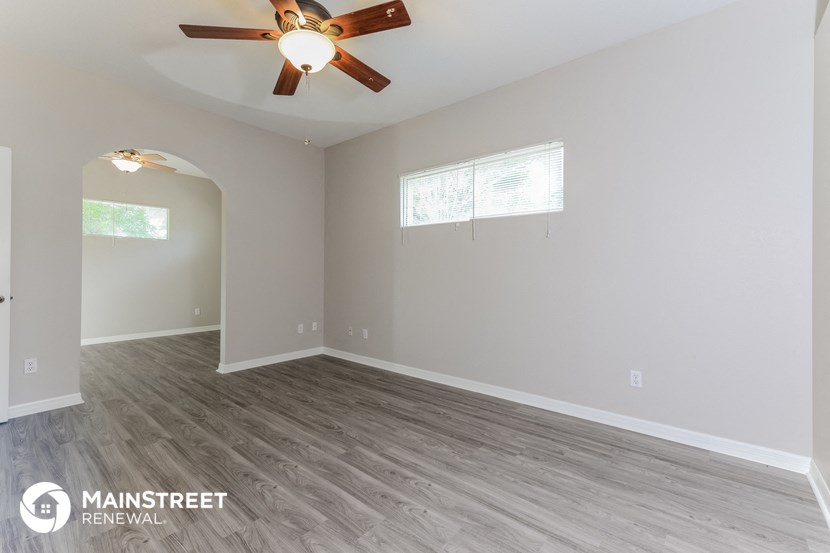 the living room of an empty house with a ceiling fan