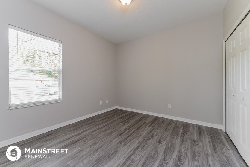 the spacious living room with wood flooring and a window