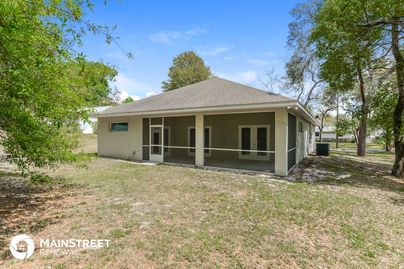 the front of the house has a porch and a large yard with trees