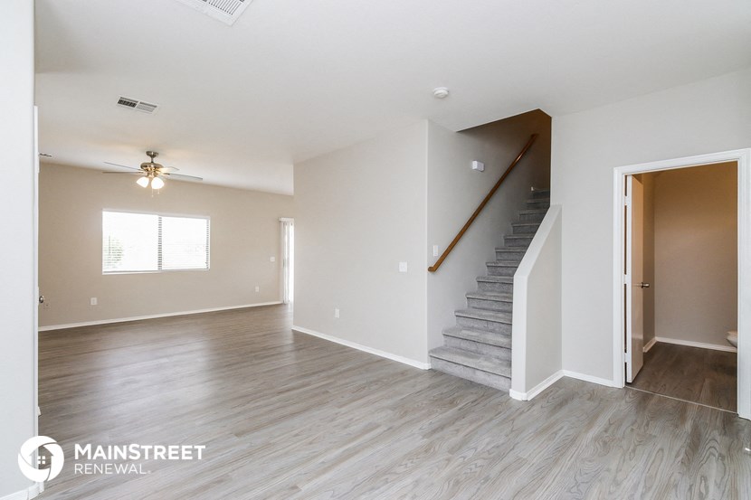 a living room with a staircase and a ceiling fan