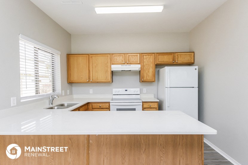 a kitchen with white countertops and wooden cabinets and a white refrigerator
