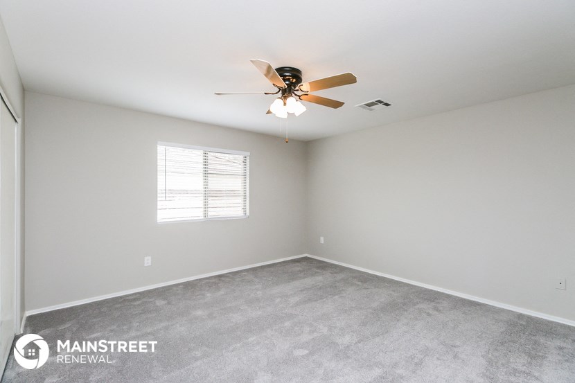 the living room of an empty home with a ceiling fan