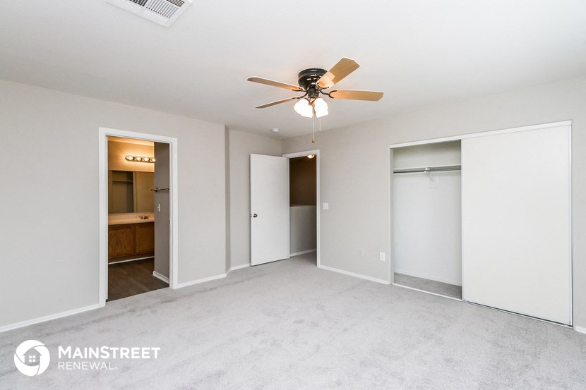 a bedroom with white walls and a ceiling fan