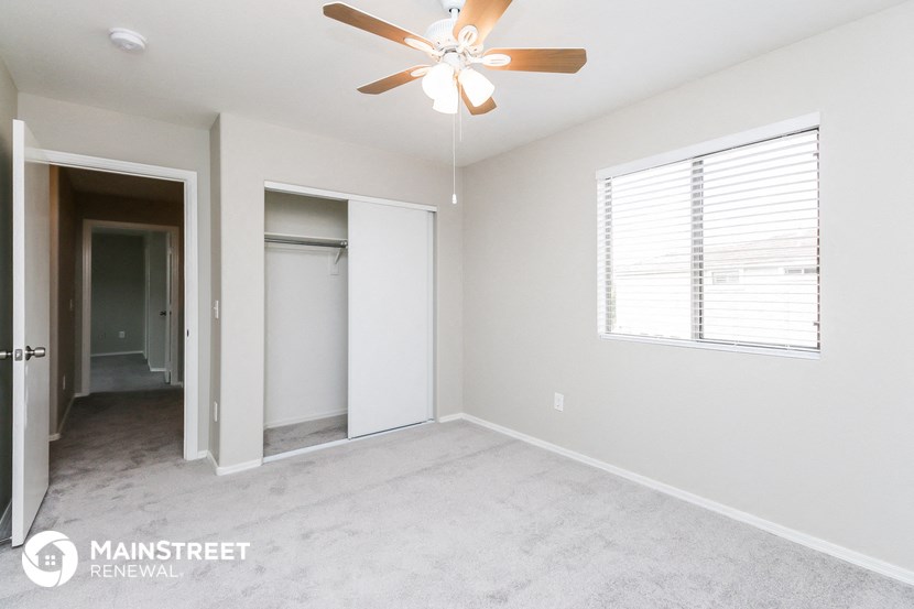 an empty bedroom with a ceiling fan and a closet