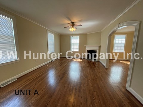 A spacious room with wooden floors and a ceiling fan.