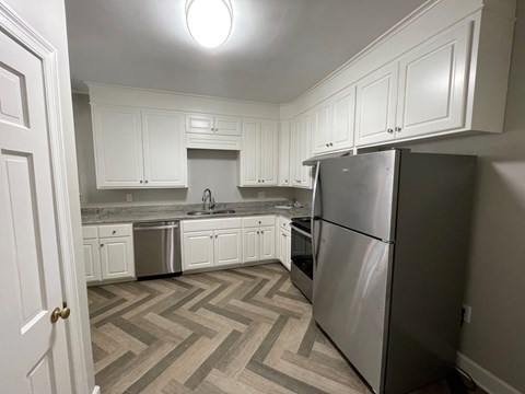 A kitchen with a refrigerator, sink, and cabinets.