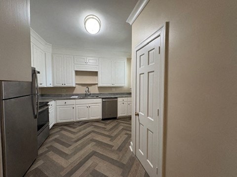 A kitchen with white cabinets and a refrigerator.