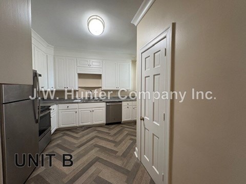 A kitchen with white cabinets and a refrigerator in the corner.