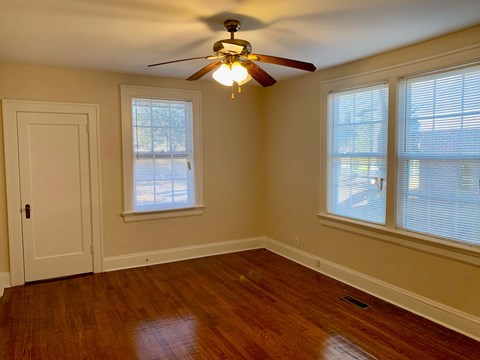 a bedroom with a ceiling fan and two windows