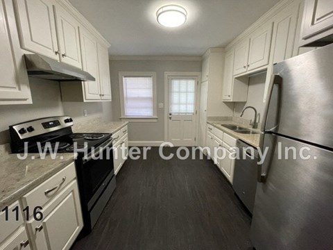 A kitchen with white cabinets and a stainless steel refrigerator.