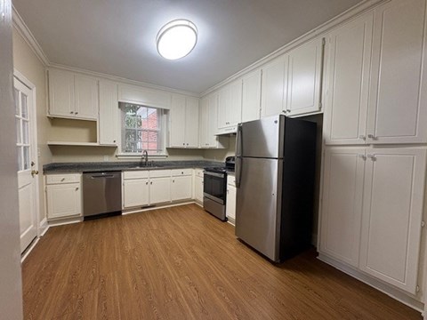 A kitchen with wooden floors and white cabinets.