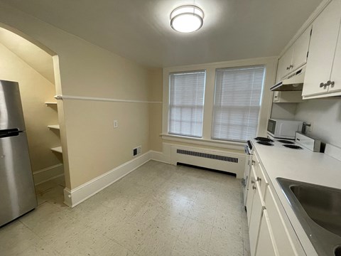 A kitchen with a refrigerator, sink, and window.